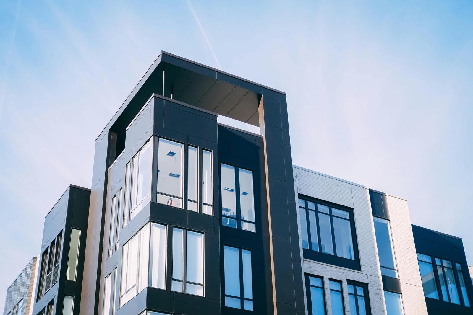 A modular commercial building in dark and light cladding against a clear sky