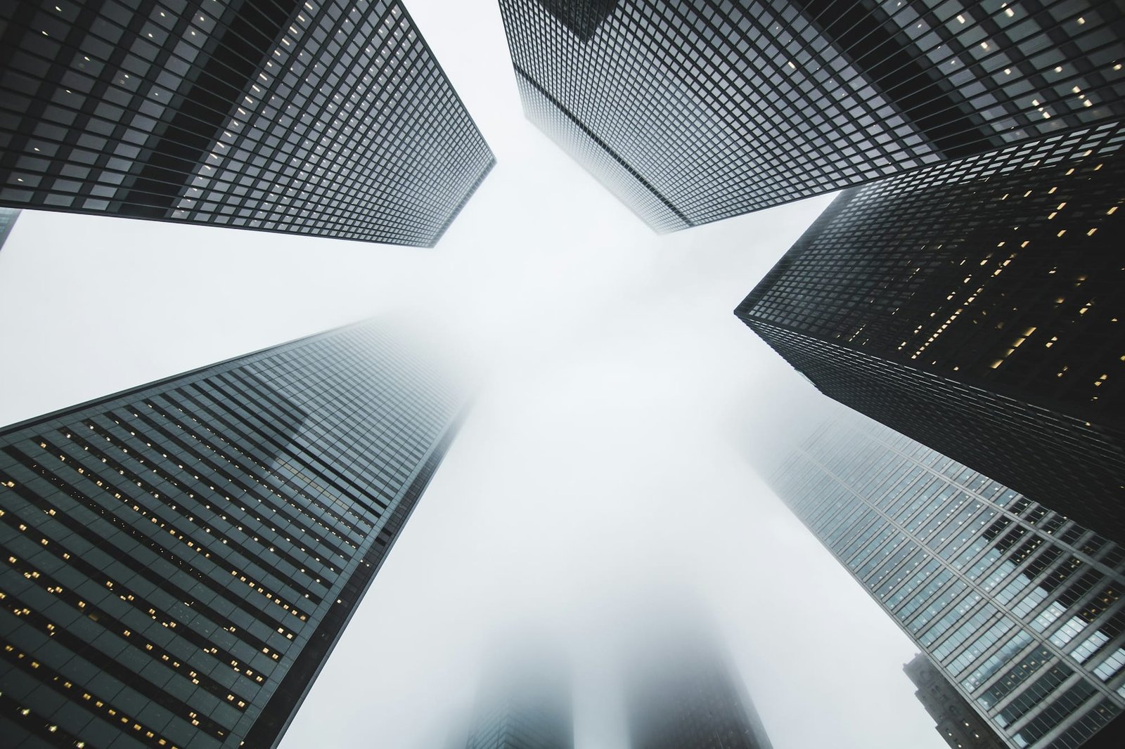 Commercial towers seen from the ground, rising into low cloud